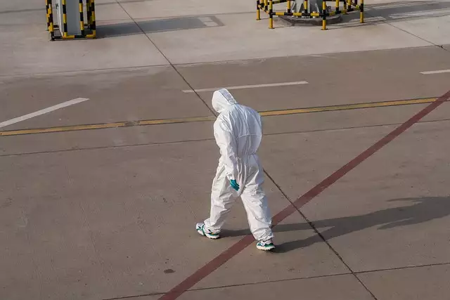 Osoba w kombinezonie ochronnym na płycie lotniska
